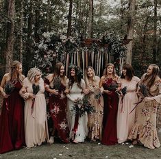 a group of women standing next to each other in front of a forest filled with trees