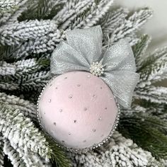 a pink ornament hanging from the top of a christmas tree with silver bows