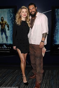 a man and woman standing next to each other in front of a movie poster at an event