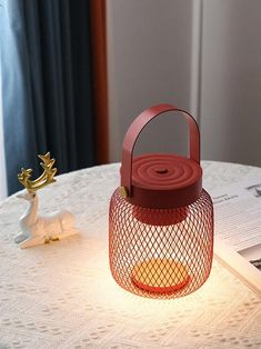 a red lantern sitting on top of a white table next to a book and candle