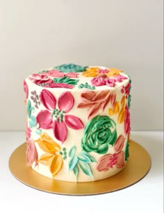 a decorated cake sitting on top of a gold platter with flowers painted on it