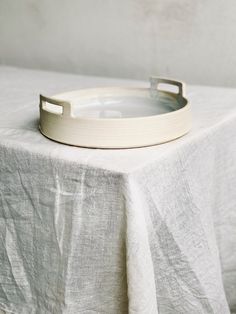 a white tray sitting on top of a table next to a gray cloth covered table