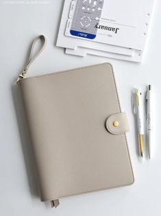 a white notebook and pen sitting on top of a table next to an id holder