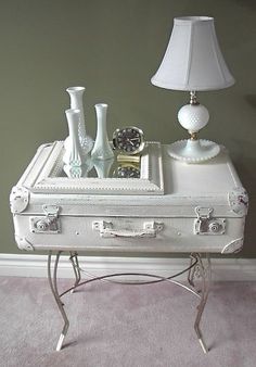 a white suitcase sitting on top of a table next to a lamp and vases