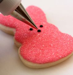 a cookie being decorated with pink frosting and a sharpie in the shape of a heart