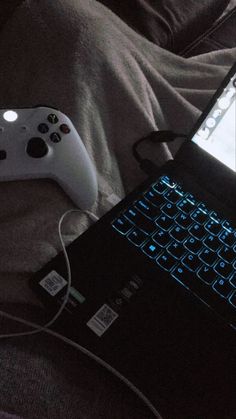 a laptop computer sitting on top of a bed next to a controller