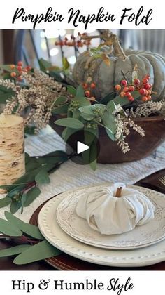 the table is set for thanksgiving dinner with white pumpkins and greenery on it