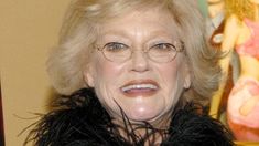 an older woman wearing glasses and a fur collar