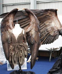 two mannequins dressed in black and brown clothing with large wings on display