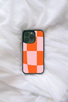 an orange and pink iphone case sitting on top of a white bed sheet with the cover pulled down