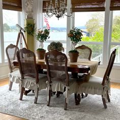 a dining room table with chairs and a chandelier in front of large windows