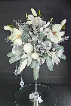 a vase filled with white flowers on top of a glass table next to a black wall