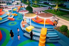 people are walking around brightly colored benches and tables in an open area with colorful flooring