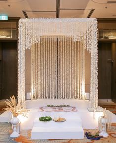 a white stage set up with chandelier and flowers on the floor in front of it