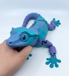 a blue and purple gecko toy being held by a hand