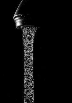 a black and white photo of a faucet with water coming out of it