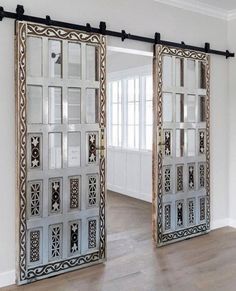 two mirrored doors in the middle of a room with wood flooring and white walls