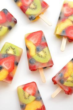 fruit lollipops are arranged on a white surface