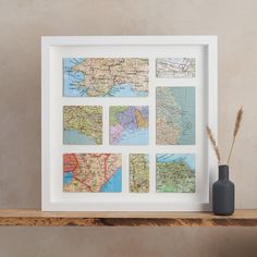 a white frame with maps on it next to a vase