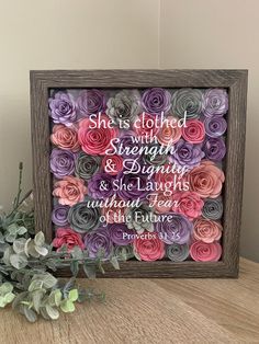 a wooden frame with flowers on it and the words she is clothed with strength and delight