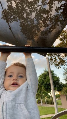 a young boy holding onto the top of a metal structure