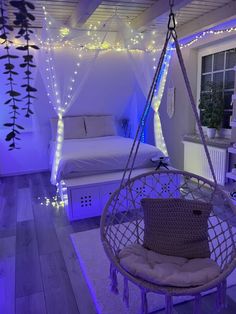 a bedroom decorated in white and purple with string lights on the ceiling, hanging hammock chair