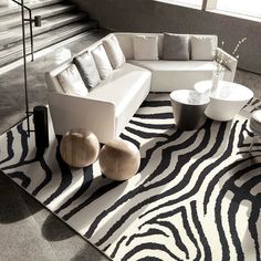 a modern living room with zebra print rug and white couches, coffee table and vases