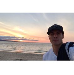 a man taking a selfie on the beach at sunset