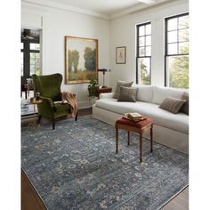 a living room filled with furniture and a large painting on the wall over a blue rug