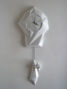 a white clock hanging from the side of a wall with an origami design on it