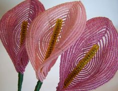 two pink flowers with yellow stamens are on a white surface and one flower has green stems