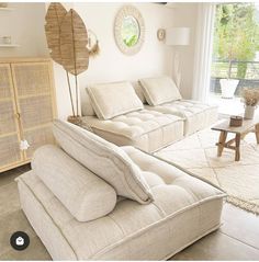 a living room filled with furniture and a large window covered in plants on top of it