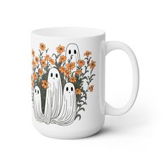 a white coffee mug with three ghost faces and orange flowers