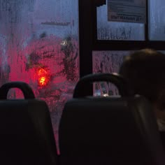 two seats in front of a frosted window with red light coming from behind it