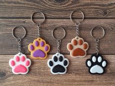 four different colored paw prints are shown on keychains, one is black, the other is white