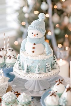 a snowman cake sitting on top of a table next to cupcakes