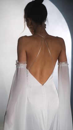 the back of a woman's white dress with long sleeves and open shoulderline