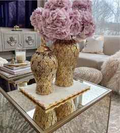 two vases with flowers are sitting on a coffee table in front of a window