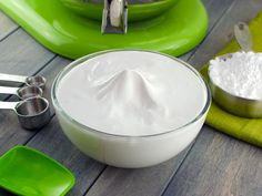 a bowl of whipped cream sitting on top of a table next to measuring spoons