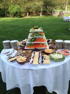 a table topped with lots of food on top of a lush green field