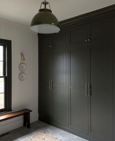 an empty room with cabinets and a bench in front of a window that looks out onto the street