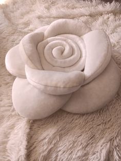 a white rose is laying on top of a fluffy blanket and it's petals are curled up