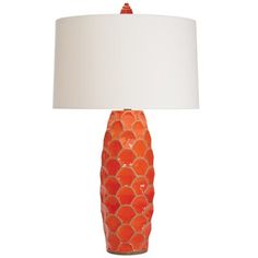 an orange ceramic lamp with a white shade on the base and a fish scale design