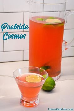 a pitcher of water and a glass filled with liquid on a counter top next to limes