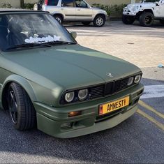 a green car parked in a parking lot next to other cars