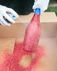 a person in white gloves is opening a cardboard box with red sand on the ground