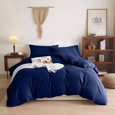 a bed with blue and white sheets in a room next to a book shelf on the floor