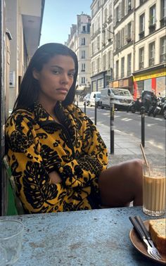 a woman sitting at a table with a drink