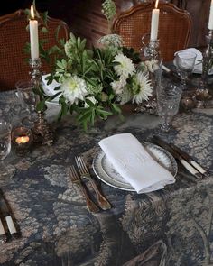 the table is set with silverware, napkins, and flowers in vases