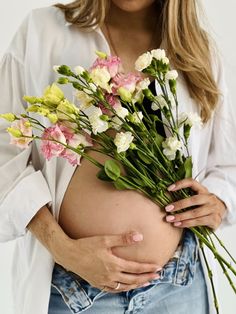 a pregnant woman holding flowers in her belly